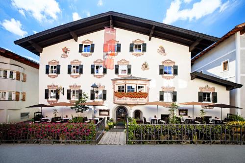 a large white building with tables and umbrellas at Eggerwirt Kitzbühel, Hotel & Restaurant in Kitzbühel