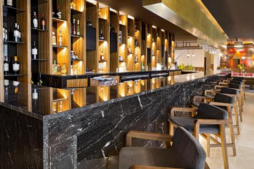 a bar with a black marble counter and wooden stools at Fiesta Americana Mexico Toreo in Mexico City