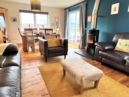 a living room with leather furniture and a table with a fireplace at Hirta Cottage in Staffin