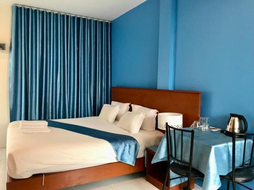 a bedroom with a bed with blue walls and a table at Grandma Kaew House in Chiang Rai