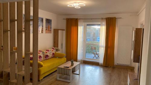 a living room with a yellow couch and a window at LCB Studio Braşov in Braşov