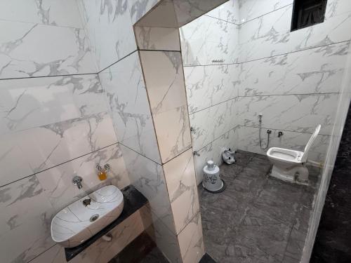 a bathroom with a toilet and a sink at Hotel Sunrise in Ādkot