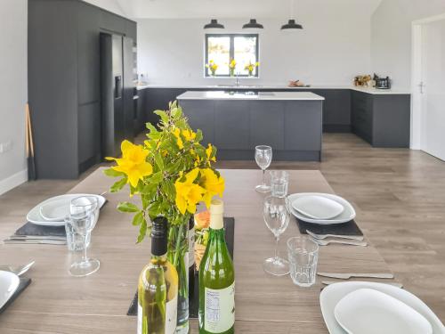 a dining table with yellow flowers and wine bottles at The Bungalow - Uk38049 in West Pennard