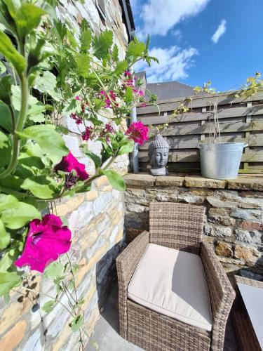 a wicker chair sitting on a brick wall with flowers at Le charme des Pierres et wellness in Ohey
