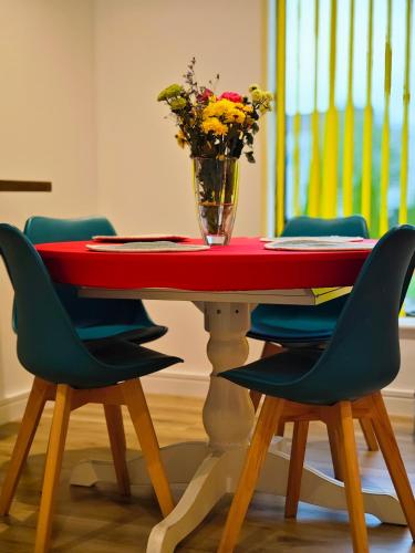 a table with chairs and a vase of flowers on it at Ashwood Stay in Galway