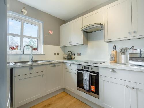 a kitchen with white cabinets and a sink and a stove at Cairnie View in Aviemore