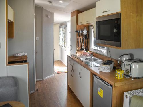 a kitchen with a sink and a microwave at Kee Holiday Home in Scratby