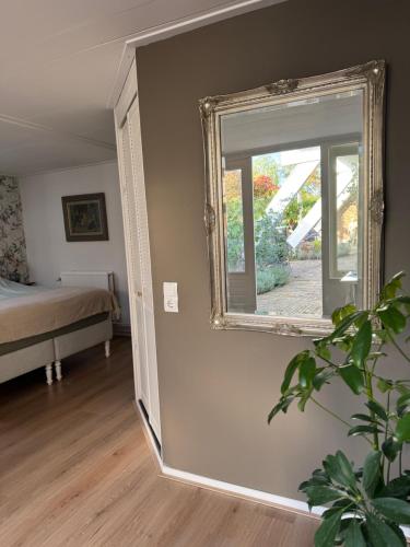 espejo en la pared en una habitación con cama en De kleine Bongerd -The little Orchard, en Hengelo