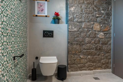 a bathroom with a white toilet and a stone wall at Ξενώνας Αγανίππη 