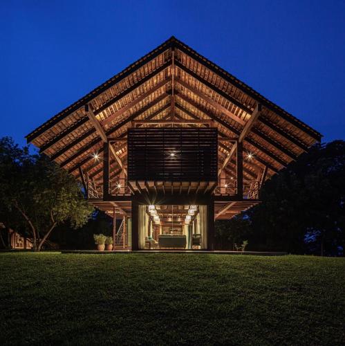 a house with a wooden roof on a grass field at Nachan The Antique Courtyard in Chiang Khan