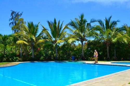 una mujer parada junto a una piscina con palmeras en Suswa Serenity, en Mombasa
