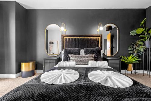 a bedroom with a large bed with two mirrors at Penthouse Noir - Wyndale Living - Central BHam 2BR in Birmingham