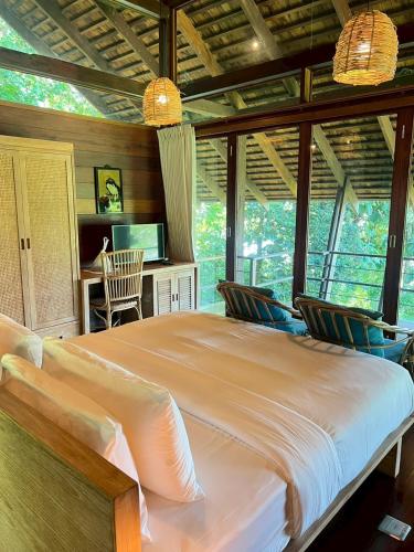 a bedroom with a large bed in a room with windows at Nachan The Antique Courtyard in Chiang Khan
