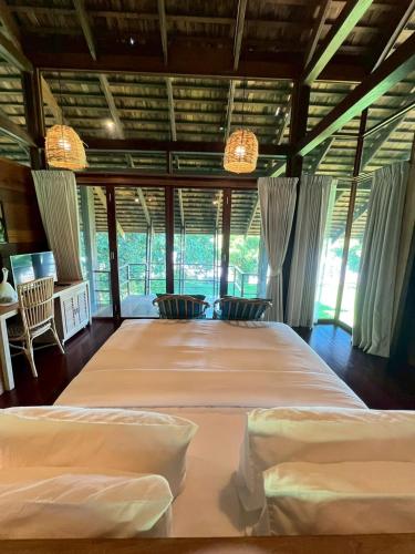 a bedroom with two beds in a room with windows at Nachan The Antique Courtyard in Chiang Khan