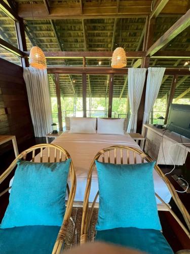 a bedroom with a bed and two chairs at Nachan The Antique Courtyard in Chiang Khan