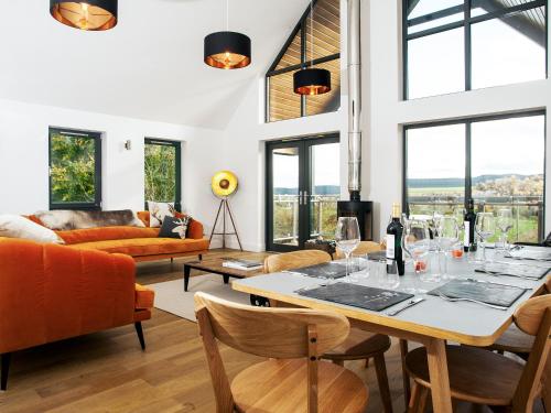 a living room with a table and chairs and windows at Strathspey Lodge in Duthil