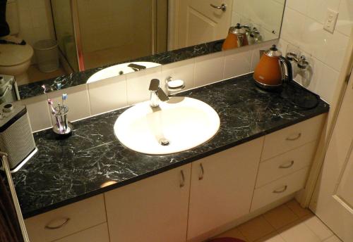a bathroom counter with a sink and a mirror at Master retreat at Private Estate Near Perth City in Perth