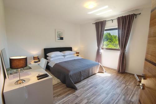 a bedroom with a bed and a desk and a window at Countryside Apartment in Rakovica