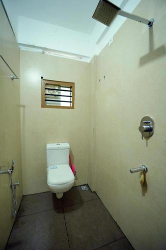 a bathroom with a toilet and a window at Haya podes in Vypīn