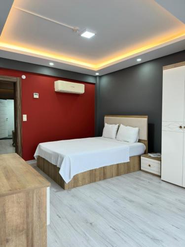 a bedroom with a white bed and a red wall at Renaissance Apart Hotel in Trabzon
