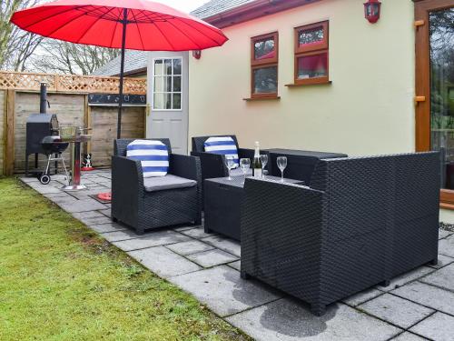 un patio avec une table, des chaises et un parasol dans l'établissement 15 Pebble Cottage, à Camelford