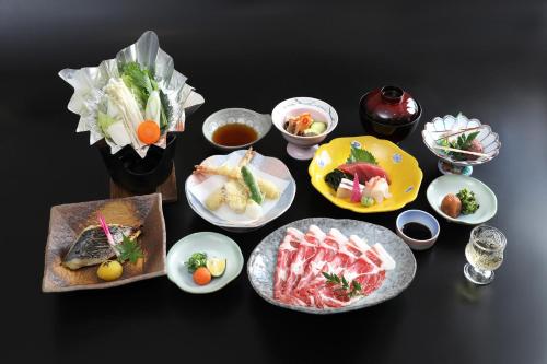 une table avec des assiettes et des bols de nourriture dans l'établissement Hotel Sunresort Shirahama, à Shirahama