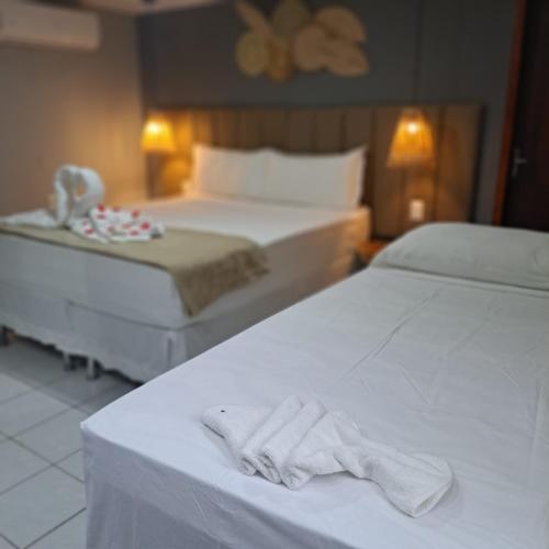two beds in a hotel room with towels on them at Pousada Villa Uçá Frances - Praia do Frances in Marechal Deodoro
