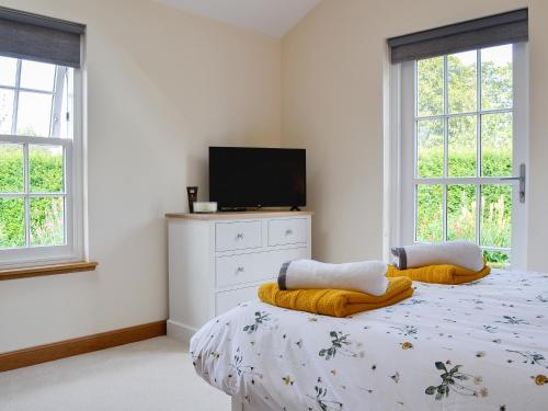 a bedroom with a bed with a tv and windows at The Garden Rooms in Montrose