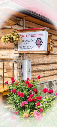 a sign on the side of a building with flowers at Pokoje Pod Cyrlicą u Józi in Chochołów
