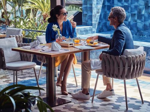 a man and woman sitting at a table in a restaurant at Sofitel Barcelona Skipper in Barcelona