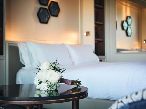 a hotel room with a bed and a table with flowers at Sofitel Barcelona Skipper in Barcelona