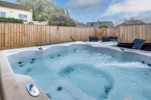 a hot tub in a backyard with a wooden fence at Mystic Heights- Wyndale Signature Stays in Worcester