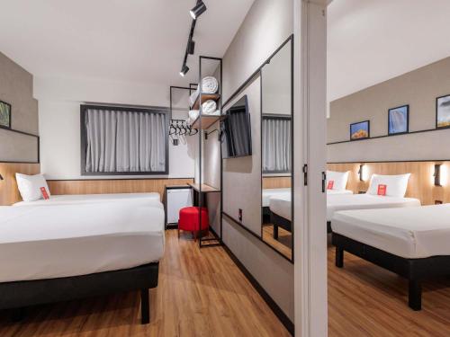 a hotel room with two beds and a hallway at Ibis Foz do Iguaçu in Foz do Iguaçu