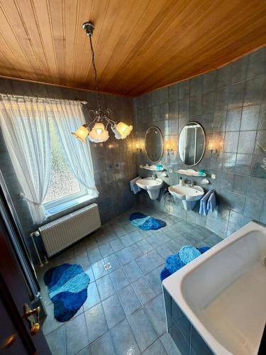 a bathroom with two sinks and a tub and two mirrors at Hotel Runge 24 7 Check In & Free Parking in Kiel