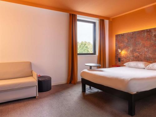 a bedroom with a bed and a chair and a window at ibis Styles Toulouse Cite Espace in Toulouse