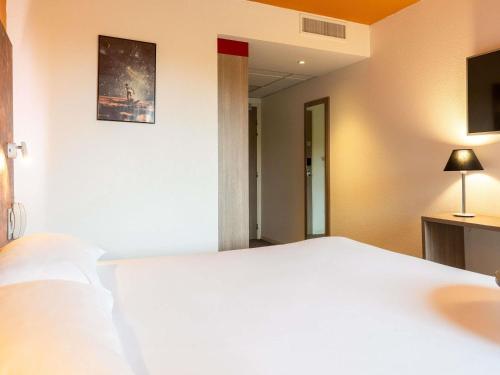 a bedroom with a large white bed and a mirror at ibis Styles Toulouse Cite Espace in Toulouse