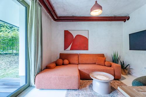 an orange couch in a living room with a window at Rezydencja Merwede Aparthotel - My Rest in Gdańsk