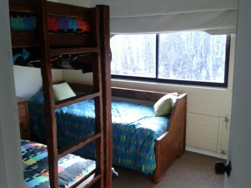 1 dormitorio con litera, 1 cama y ventana en Apartamento Termas de Chillán, en Nevados de Chillán