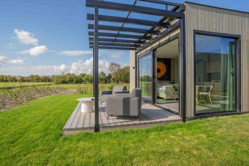 a glass house with chairs and a table in the grass at Buitenplaats Hotel met terras, studio in Ellemeet
