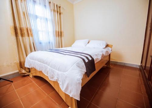a bedroom with a bed with white sheets and a window at Sereno Milele in Arusha