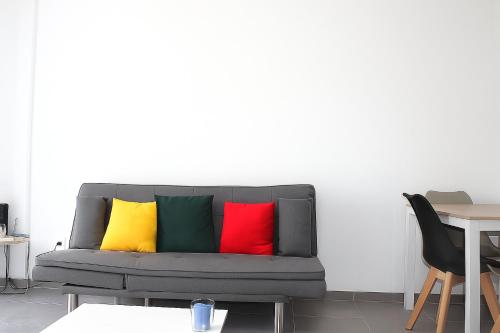 eine graue Couch mit vier bunten Kissen darauf in der Unterkunft Ola Azul Bungalow in Benidorm