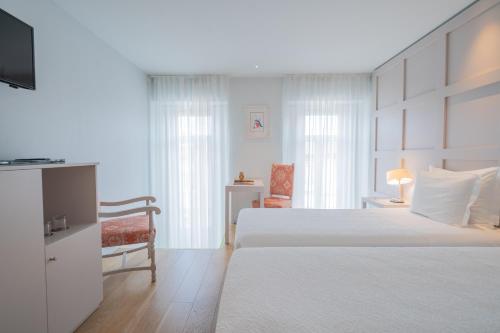a white bedroom with two beds and a chair at Burgus Tribute & Design Hotel in Braga