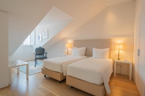 a bedroom with a bed with white sheets and a chair at Burgus Tribute & Design Hotel in Braga