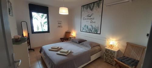 a bedroom with a bed with two towels on it at Appt Monoï meublé 4 étoiles à 300m du Lagon St Leu in Saint-Leu