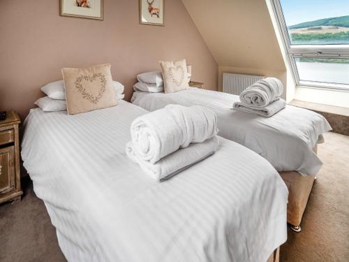 three beds in a room with white towels on them at Chapelburn in Lawers