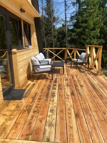 a wooden deck with two chairs on a house at Brda 5 osobowa z jacuzzi in Zawoja