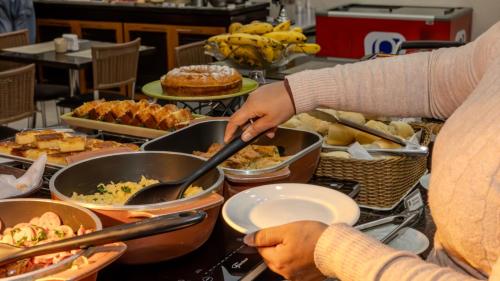 a person is preparing food in pots on a buffet at Nobile Inn Jundiaí in Jundiaí