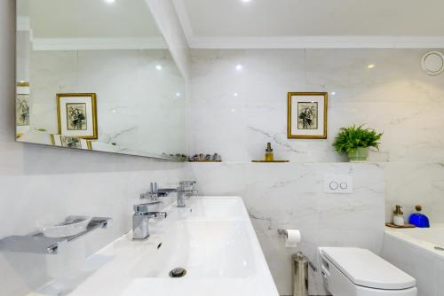 a white bathroom with a sink and a toilet at Dolphin beach Apartment -Kite beach in Cape Town