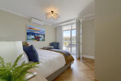 a bedroom with a bed and a large window at Dolphin beach Apartment -Kite beach in Cape Town
