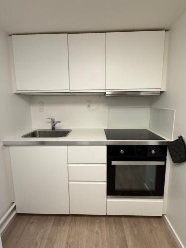 a white kitchen with a sink and a stove at Cozy Apartment near the Center of Aalborg in Nørresundby
